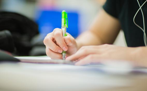 Person writing on paper with a pen